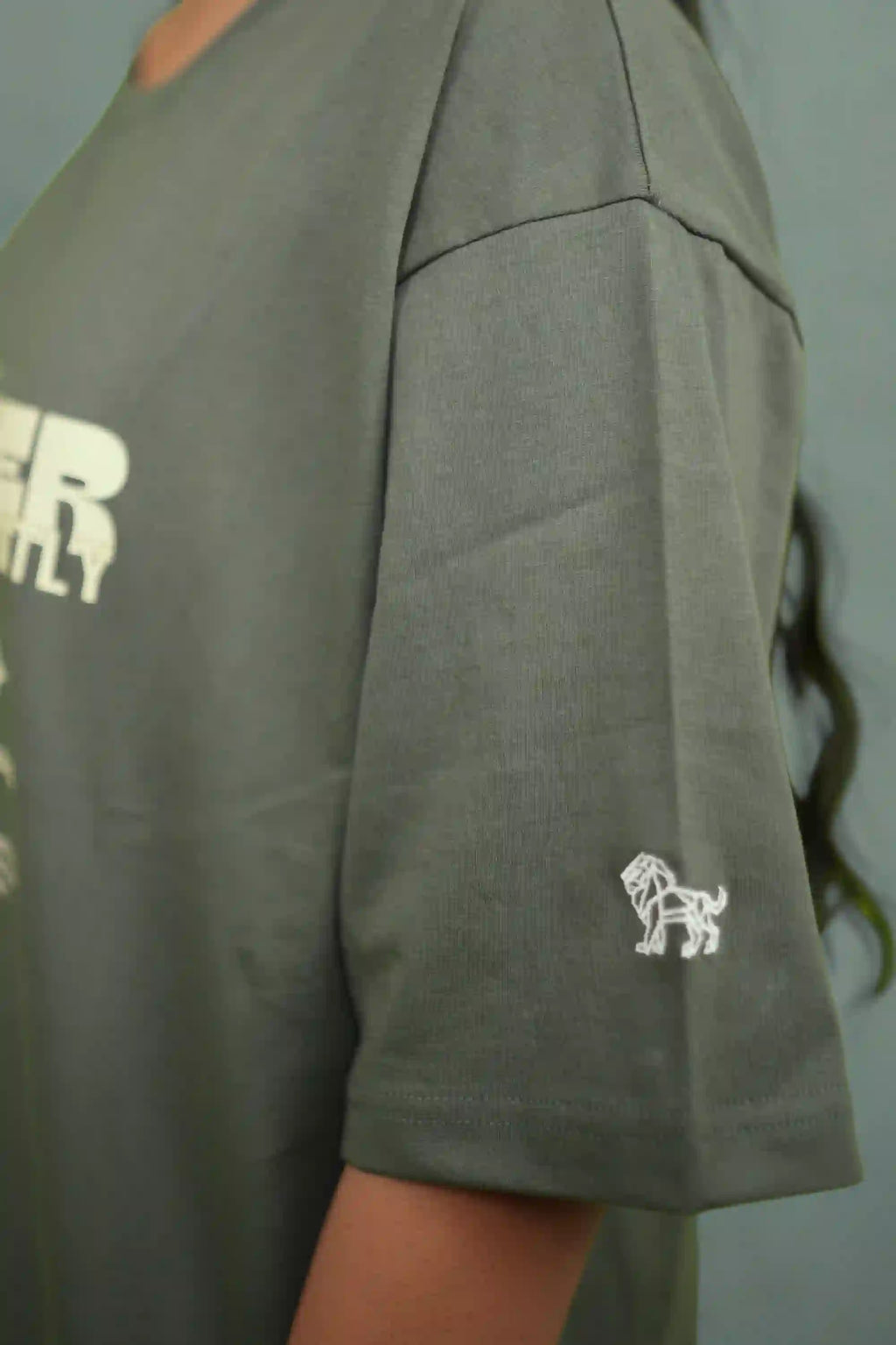 Green t-shirt with a logo on the sleeve against a plain background